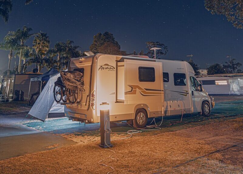 a camper parked next to a tree at night